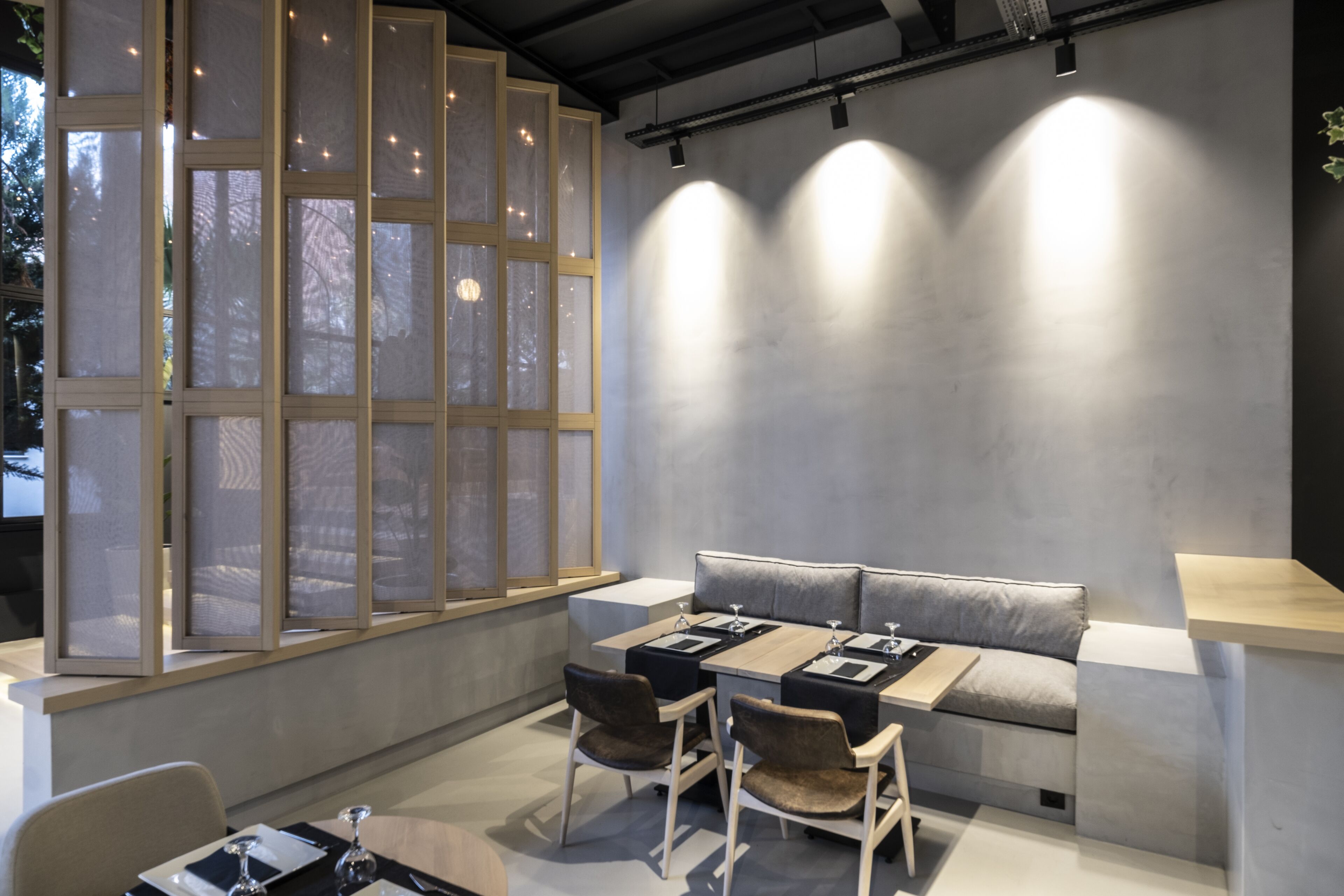 A modern dining area with a large window, a sofa, and a table set for four.