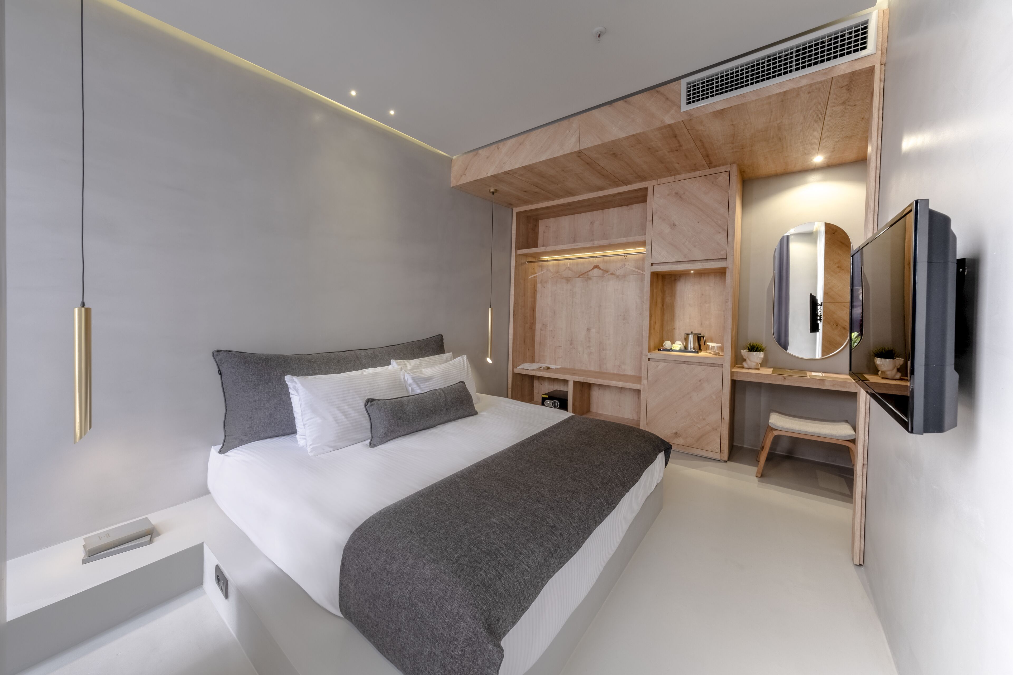Une chambre à coucher moderne avec un grand lit, un bureau intégré, une coiffeuse et un téléviseur fixé au mur.