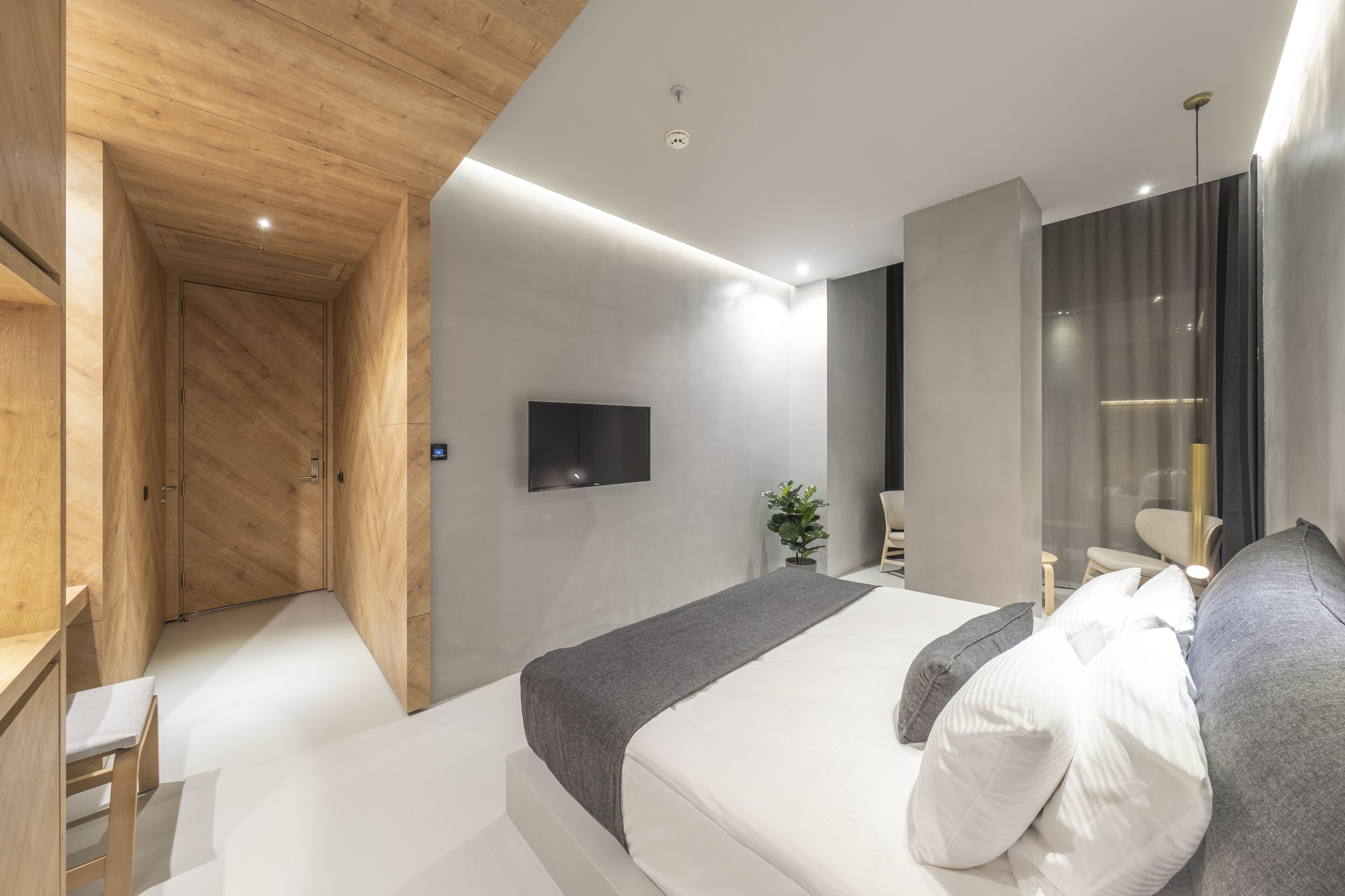 Un dormitorio moderno con una cama grande, un televisor montado en la pared y un armario de madera.