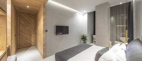 Un dormitorio moderno con una cama grande, un televisor montado en la pared y un armario de madera.