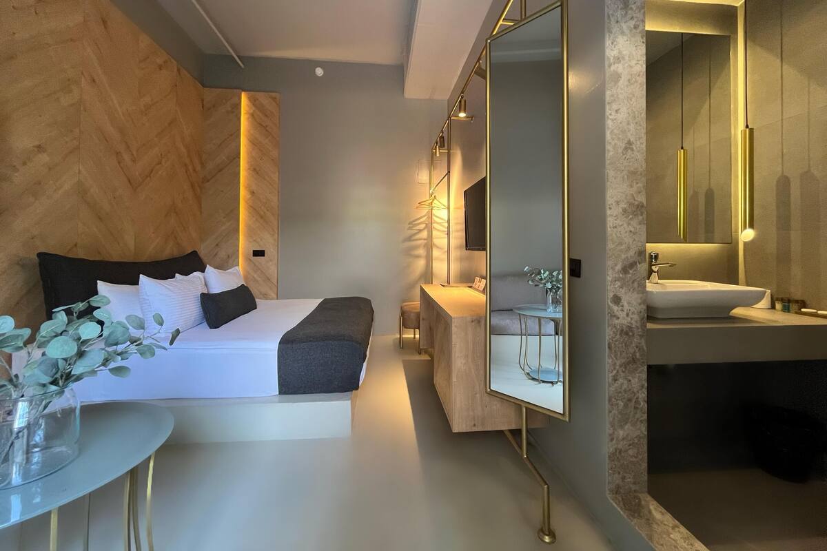 Ein modernes Hotelzimmer mit Bett, Nachttisch und einem großen Spiegel.