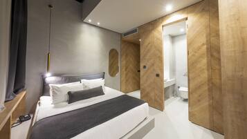 A modern bedroom with a large bed, wooden wardrobe, and a bathroom visible through an open door.
