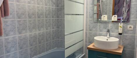 A modern bathroom with a glass-enclosed shower, a white sink, and a teal vanity.