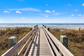 A wooden boardwalk leading to a beach with a clear sky. - Classic oceanfront beach escape! (North Myrtle Beach)