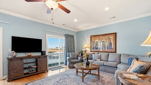 A living room with a large flat-screen TV, a sofa set, a coffee table, and a painting on the wall. - Stunning marsh view home, gorgeously furnished, private pool - walk to beach - perfect area (North Myrtle Beach)