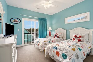 A bedroom with two beds, a TV, and a balcony with a view.