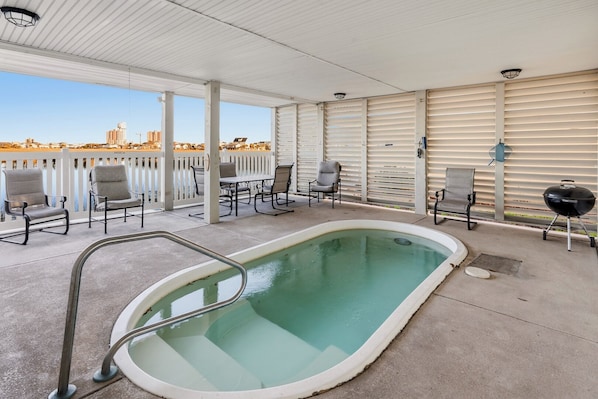 An outdoor pool area with a pool, lounge chairs, and a barbecue grill.