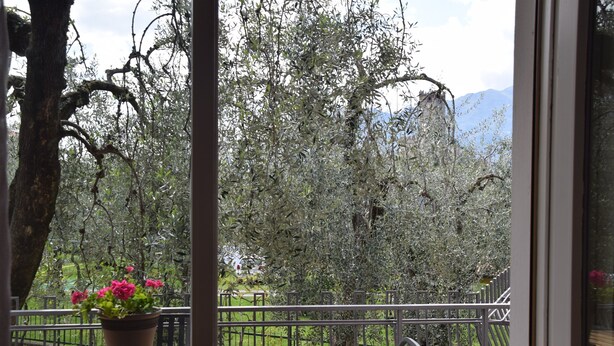 Un balcone con tavolo e sedie di legno, circondato da una ringhiera in metallo.