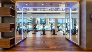 Een moderne sportschool met houten vloeren, spiegelwanden en diverse fitnessapparaten.