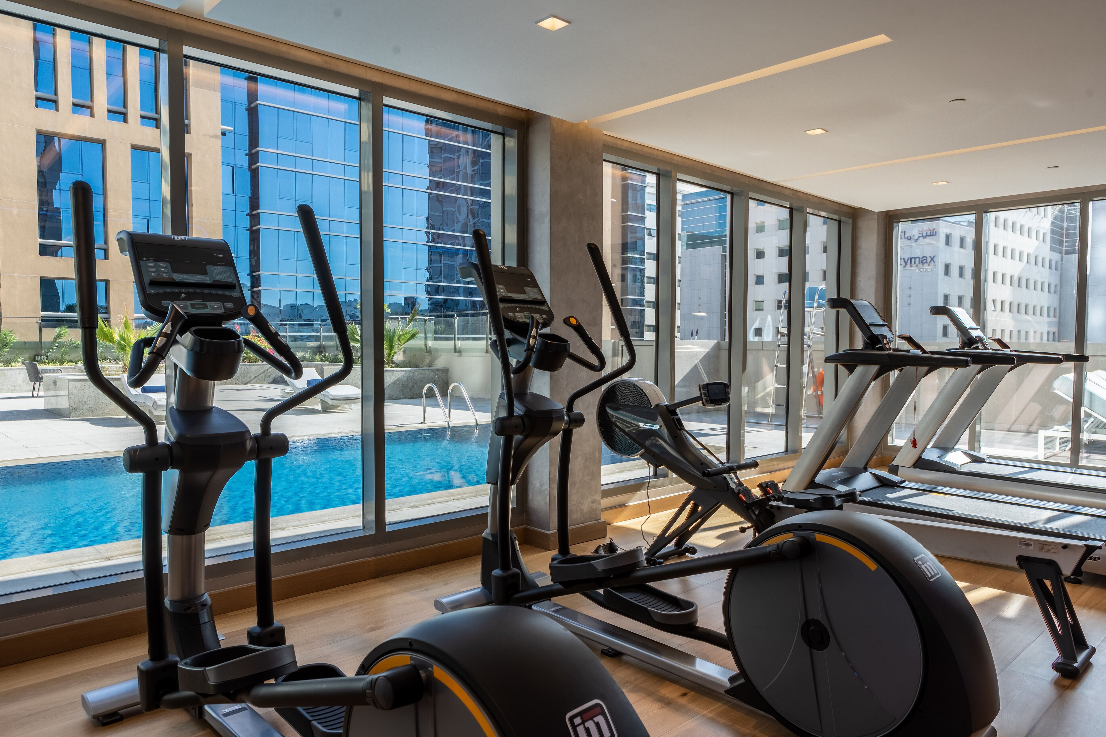 A gym with cardio equipment and a view of a swimming pool.