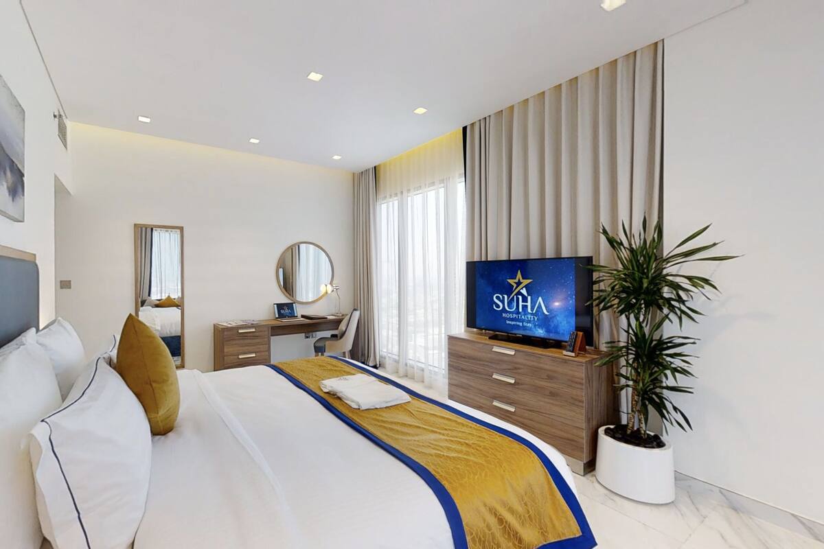 Une chambre d’hôtel moderne avec un grand lit, un bureau, une télévision et une plante en pot.