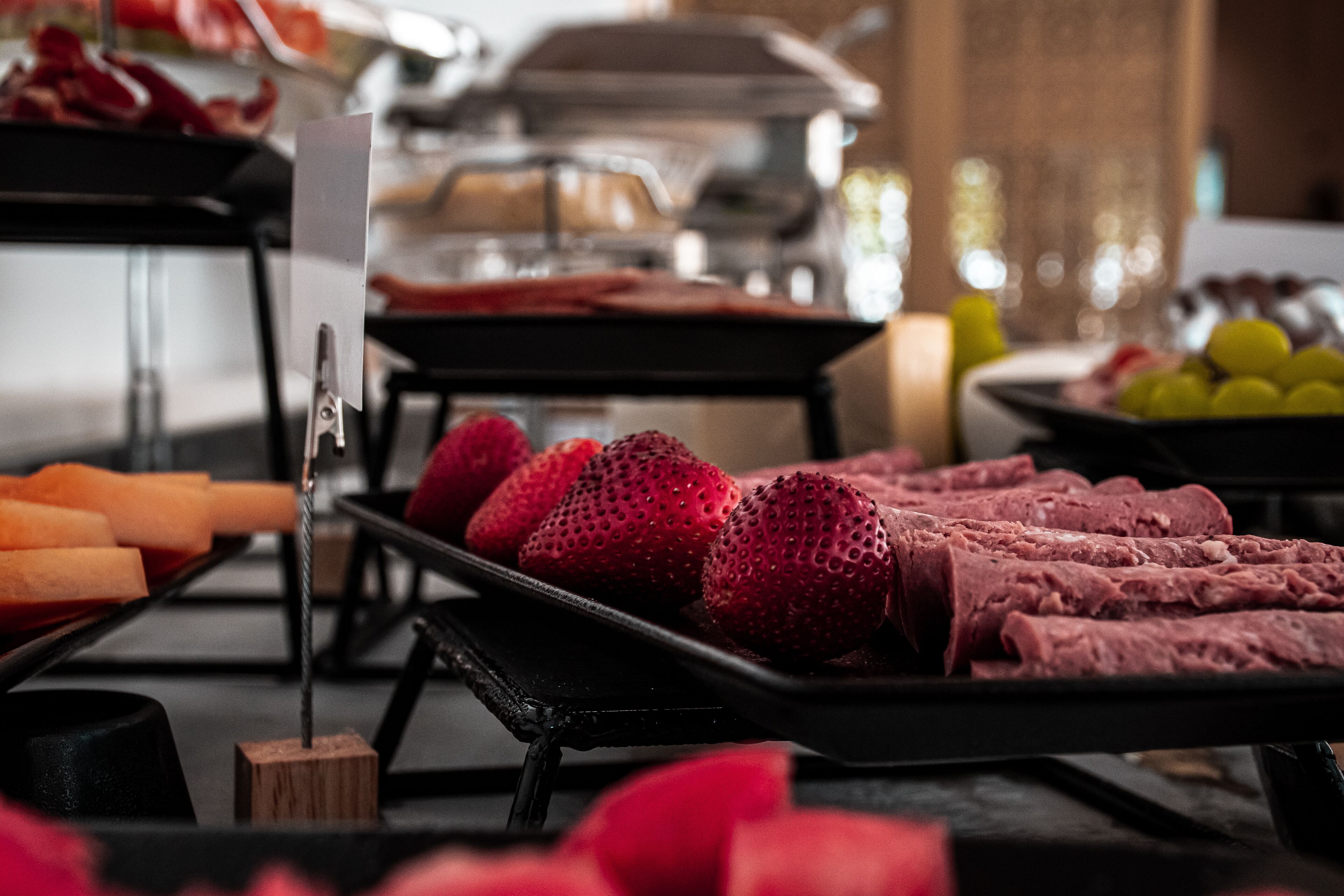 A buffet with various food items including strawberries and sliced meats.
