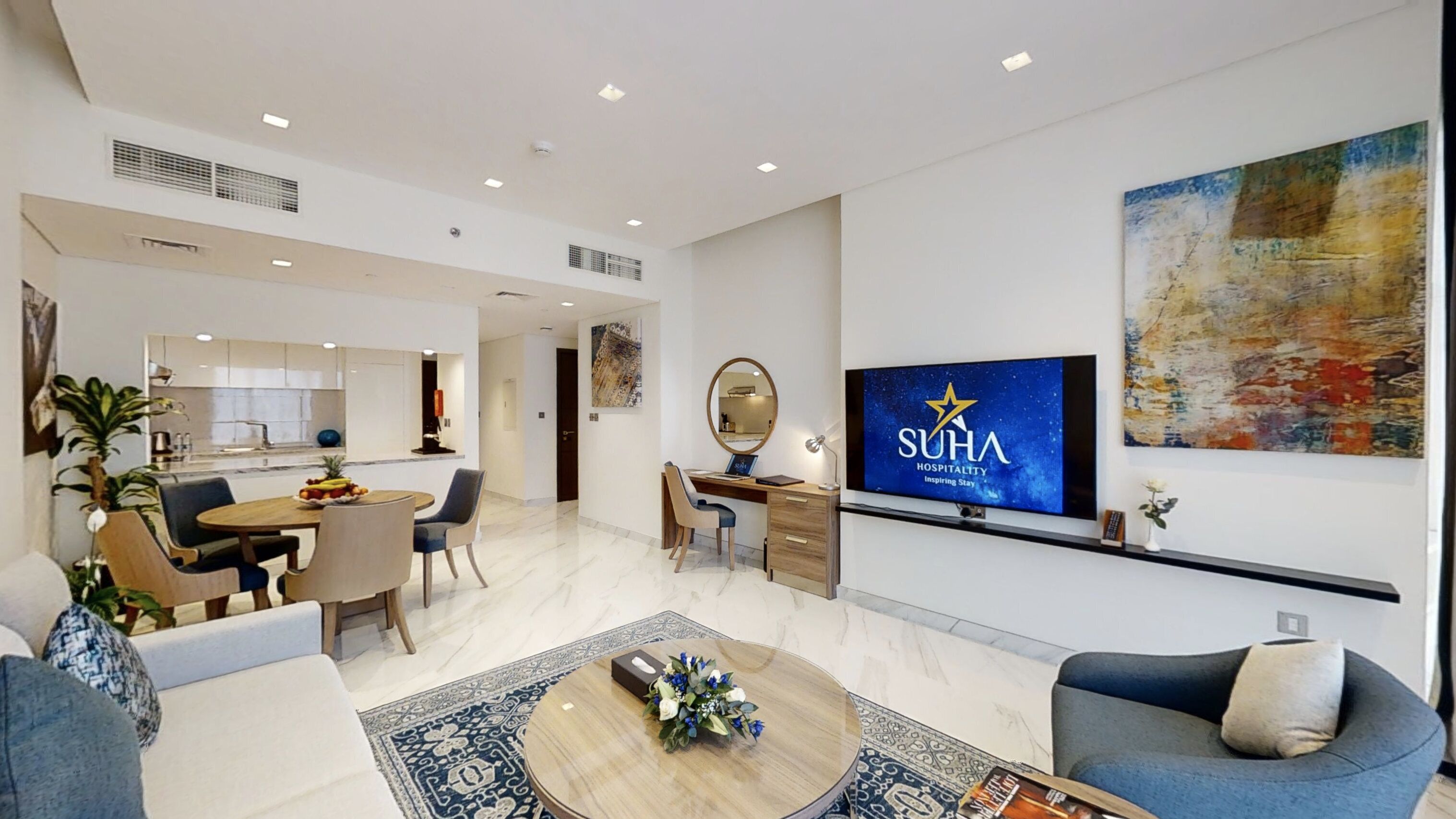 A modern hotel room with a dining area, a workspace, and a living area.
