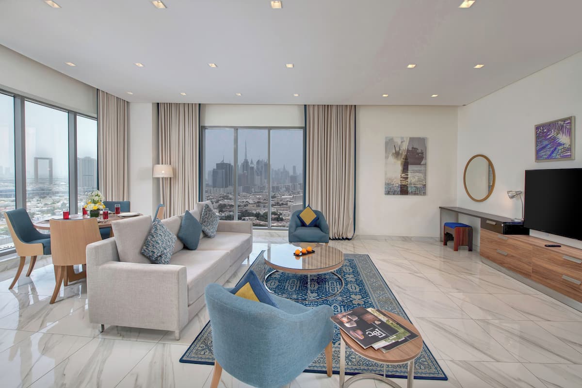Un salon moderne avec un canapé, des fauteuils, une table basse et un téléviseur.
