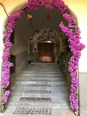 Una escalera con un arco floral que lleva a una puerta.