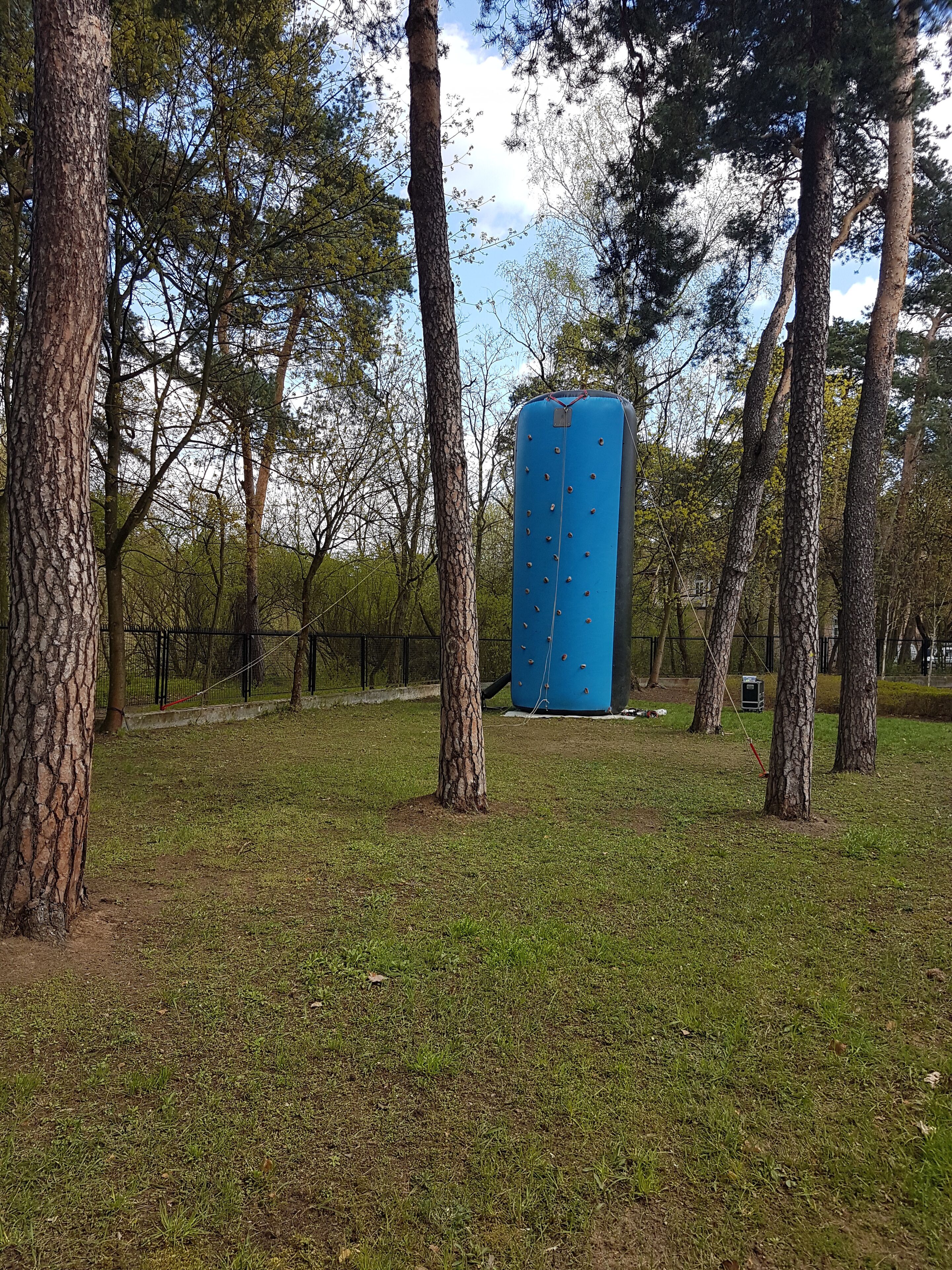 A blue cylindrical structure in a grassy area surrounded by trees.