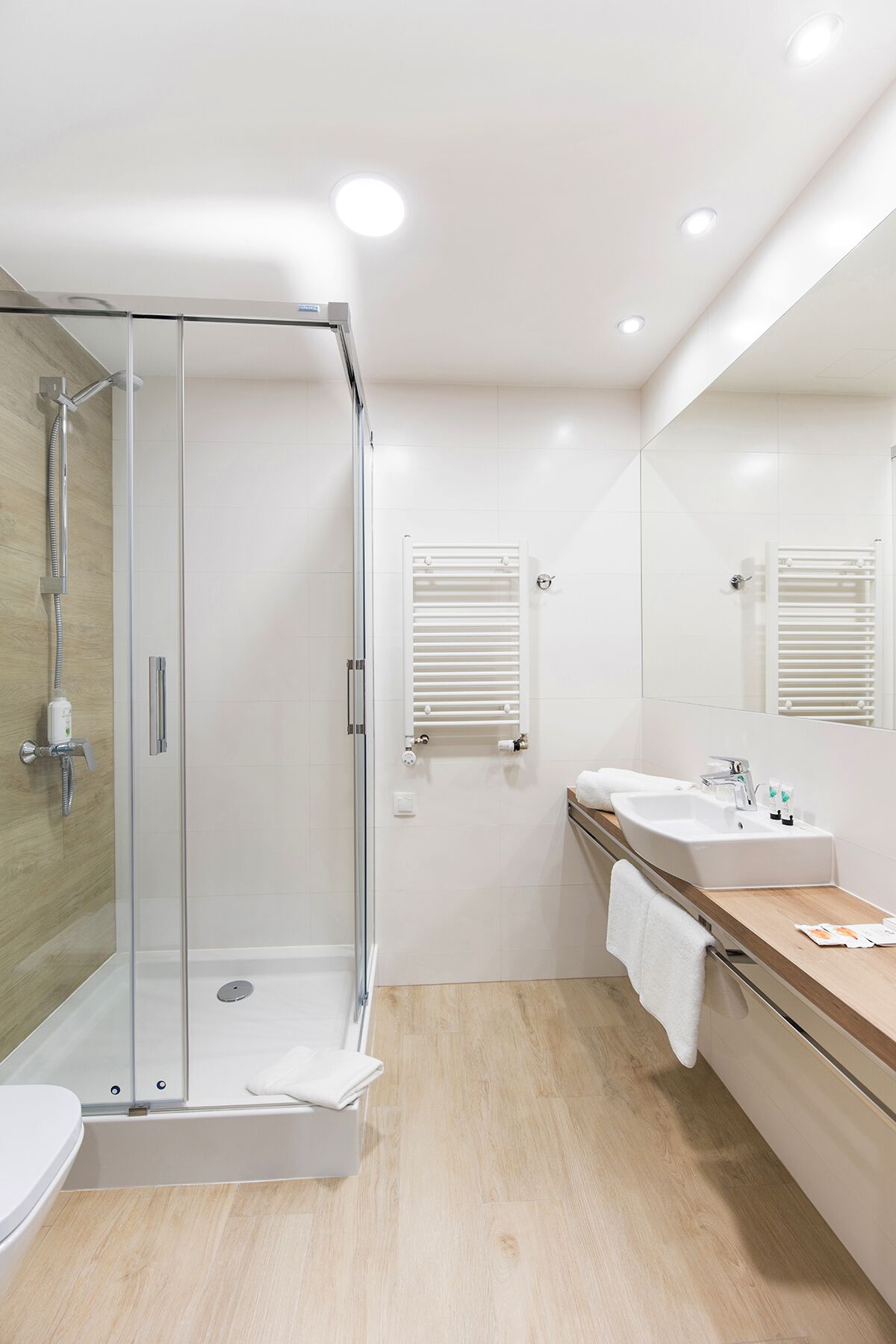 Une salle de bain moderne avec une douche à parois de verre, un lavabo avec un miroir et un porte-serviettes.
