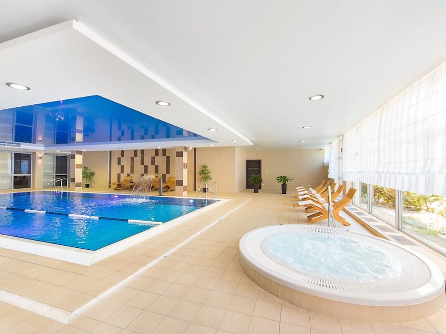 Een binnenzwembad, ligstoelen bij het zwembad, badmeesters op locatie