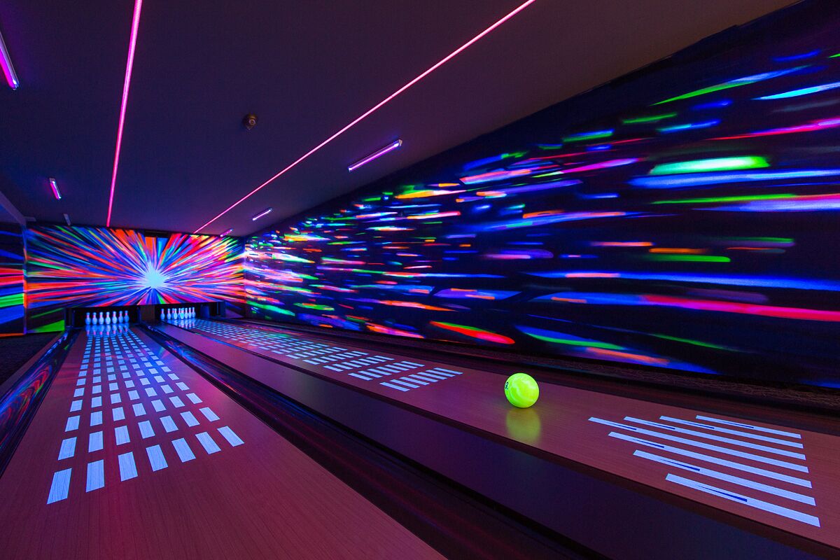 Une salle de bowling avec des néons et une boule de bowling sur la piste.