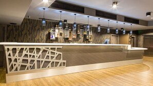 A modern reception area with a wooden floor, a white reception desk with a geometric pattern, and pendant lighting. - Z-Hotel Business & Spa (Otwock)