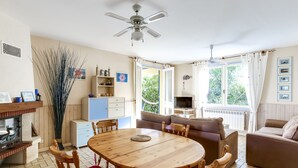 A cozy living room with a wooden dining table, chairs, a sofa, and a television. - Cozy Villa Steps from Beach in Biscarrosse - WiFi, Terrace, Garden, Sleeps 6 (Biscarrosse Plage)