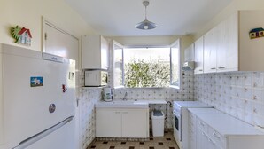 A compact kitchen with white cabinets, a refrigerator, a microwave, and a window providing natural light. - Cozy Villa Steps from Beach in Biscarrosse - WiFi, Terrace, Garden, Sleeps 6 (Biscarrosse Plage)