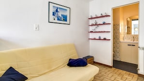 A small, well-lit room with a yellow sofa, a framed picture of a building, and a wooden floor. - Cozy Villa Steps from Beach in Biscarrosse - WiFi, Terrace, Garden, Sleeps 6 (Biscarrosse Plage)