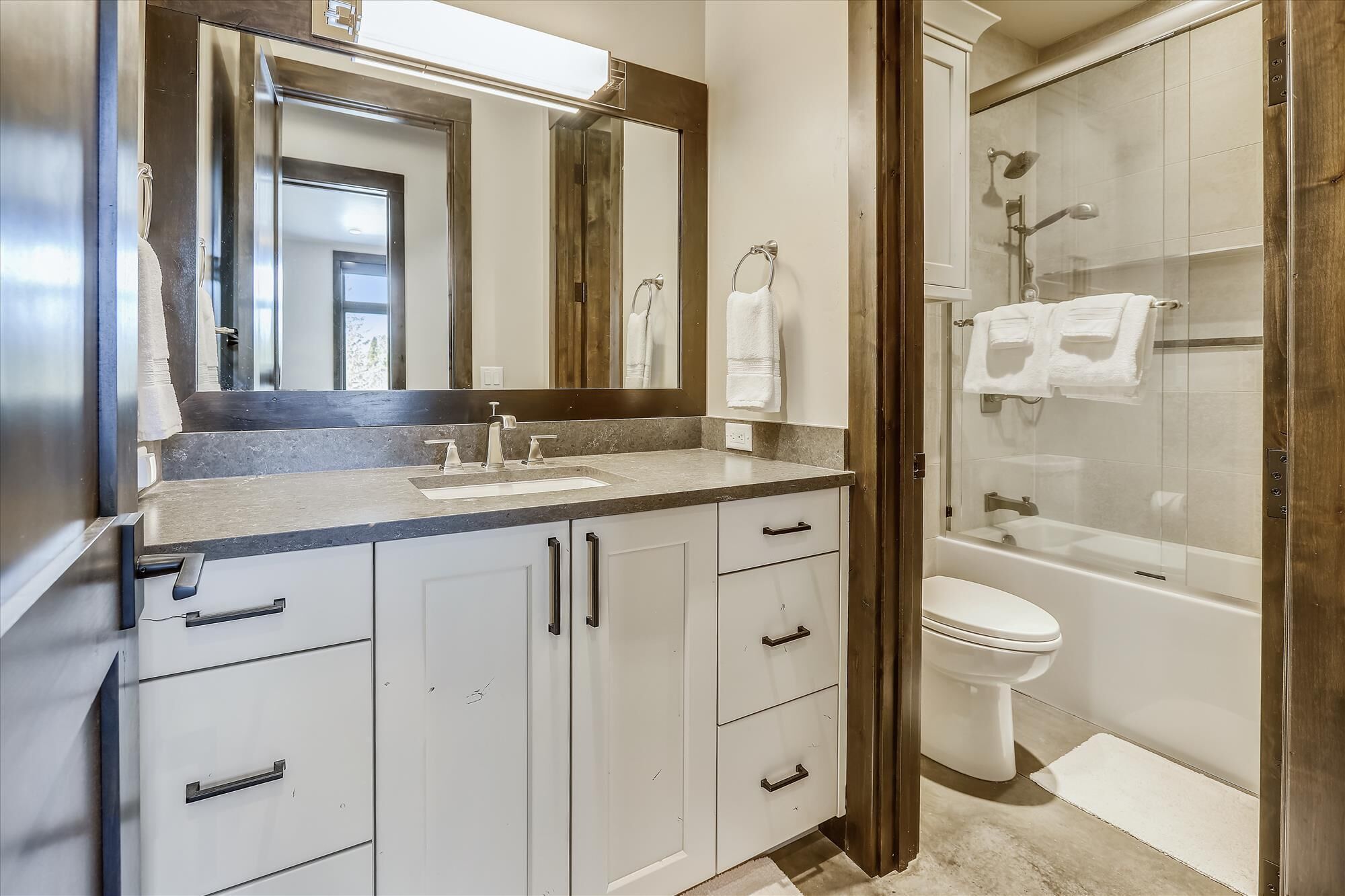 A modern bathroom with a sink, mirror, and toilet.