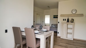 A dining area with a white table and chairs, a wooden cabinet, and a clock on the wall. - House stefi 2 M0230450730 (Malcesine)