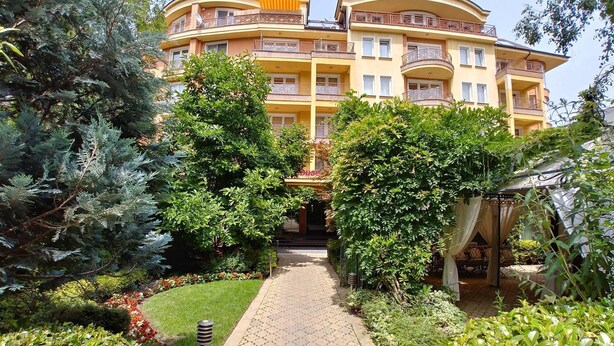 A multi-story building with balconies, surrounded by lush greenery and a paved pathway. - Aparthouse Borovo (Sofia)