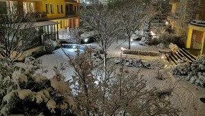 A snow-covered courtyard with a bridge, buildings in the background, and a well-lit pathway. - Aparthouse Borovo (Sofia)