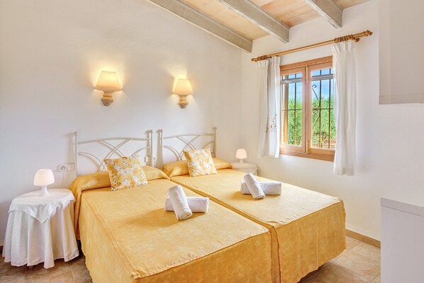 Ein Doppelbett mit zwei Kissen, ein Nachttisch mit Lampe und ein Fenster mit Vorhängen.