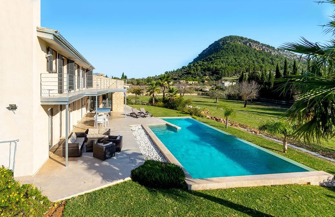 Une propriété résidentielle dotée d’une piscine, d’un espace extérieur aménagé et offrant une vue sur un paysage montagneux.