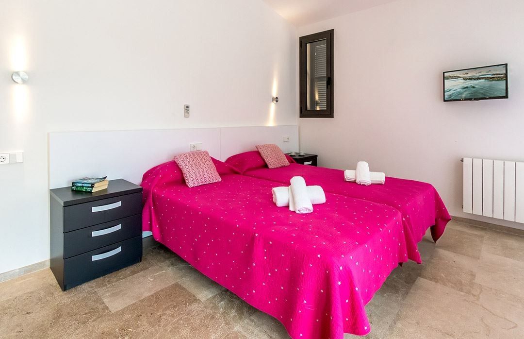 Une chambre avec deux lits, une table de chevet, un radiateur et un téléviseur fixé au mur.