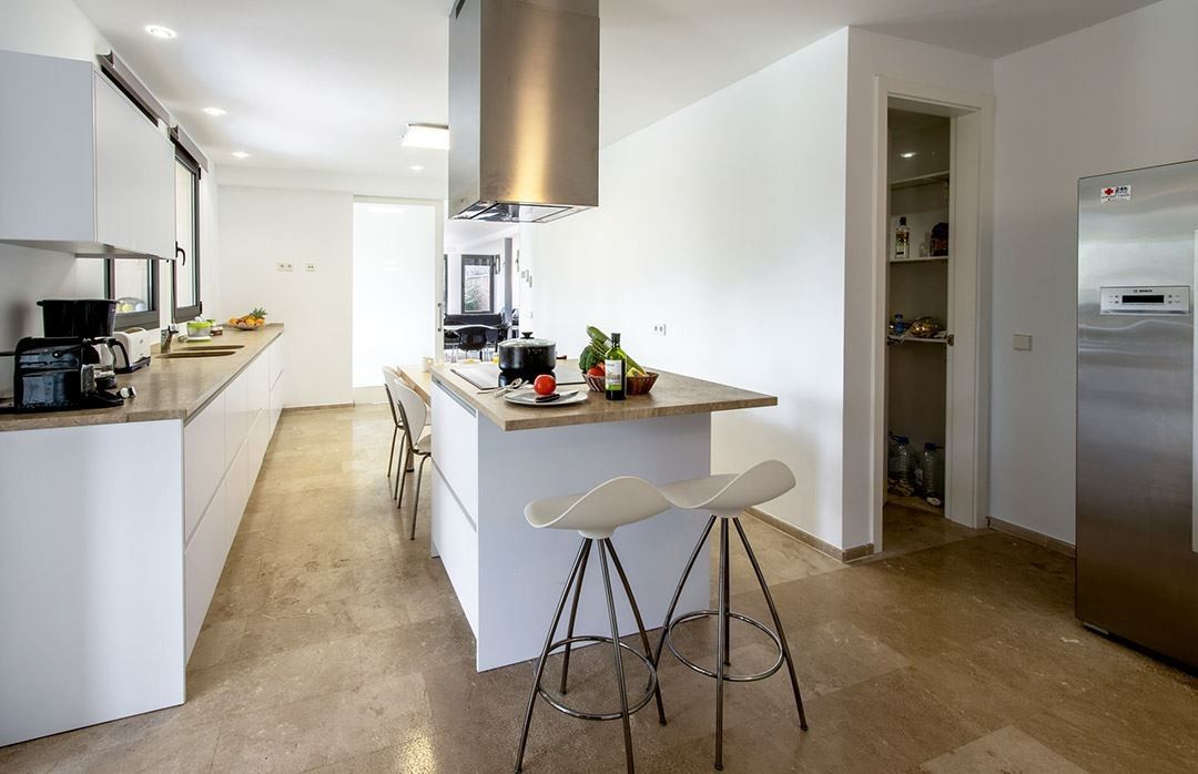 Une cuisine moderne dotée d’un îlot central, de tabourets de bar et d’un four encastré.