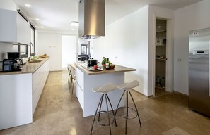 A modern kitchen with a central island, bar stools, and a built-in oven.