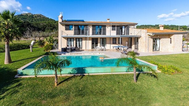 Une maison à deux étages avec une piscine, un espace salon extérieur et une vue sur une montagne.