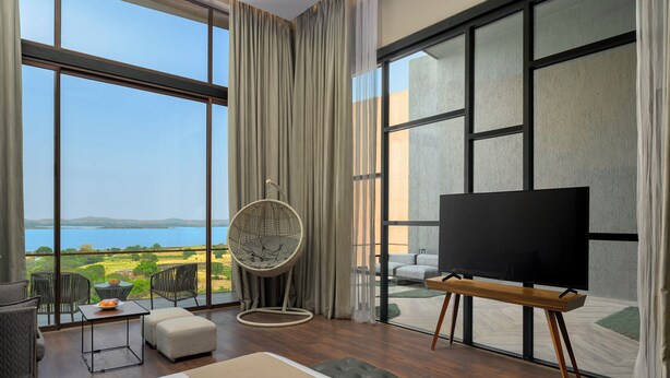 Amplia habitación con una cama grande, televisión y vistas a un lago.