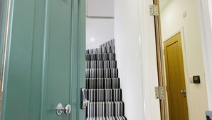 A staircase with striped carpet, a green door, and a wooden door.