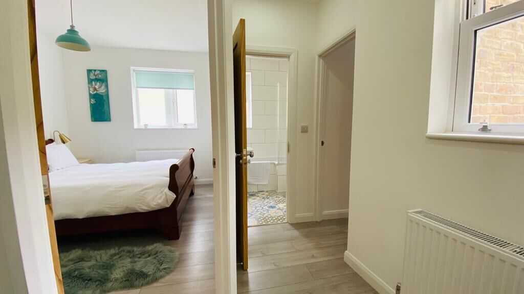 Un dormitorio con una cama, una alfombra verde, una ventana y una puerta que da al baño.