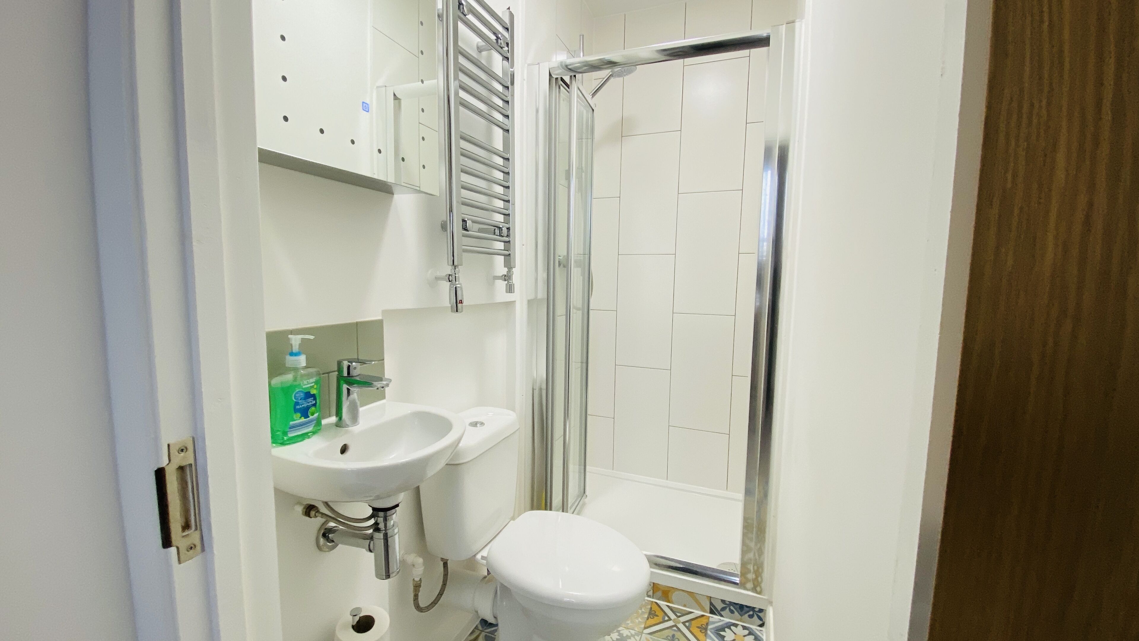 A bathroom with a shower, two sinks, and a toilet.
