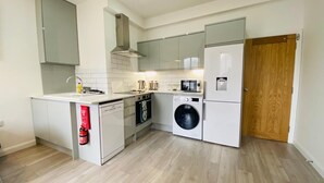 A compact kitchen with a dishwasher, washing machine, and a microwave.