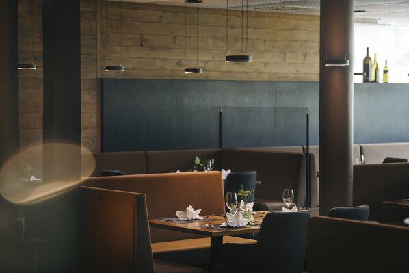 A restaurant interior with wooden walls, modern pendant lighting, and a clean, minimalist table setting. - Almhof Family Resort & SPA (Gerlos)