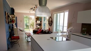 A spacious kitchen with a large island, a dining area, and a view of the outdoors. - Il Sole di Poggi (Imperia)