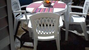 An outdoor patio with a round table and white chairs, surrounded by a blue gate and a white wall. - Sun, sea and easy living in this studio close to everything (SAINT FRANCOIS)