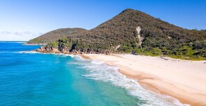 A beach with clear turquoise waters and a mountain in the background.