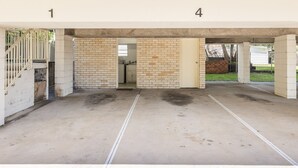 A parking garage with concrete floors and brick walls, featuring a visible door and a small window. - Shoal Court 4, 7 Lillian St - water views , linen, bed making (Shoal Bay)