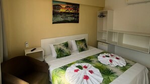 Una habitación de hotel con una cama, una silla, un cuadro y un televisor.