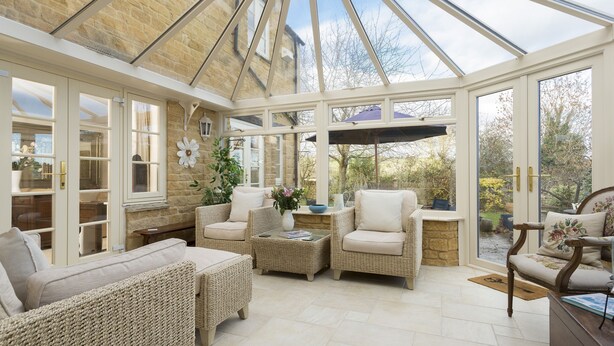 A conservatory with wicker furniture, a stone wall, and a view of the garden. - Chipping Campden Modern House, Garden, upstairs/downstairs bedrooms/bathrooms.  (Chipping Campden)