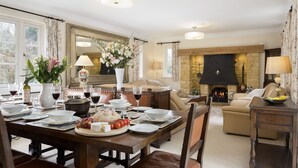 A dining area with a table set for four, a fireplace, and a sofa in the background. - Chipping Campden Modern House, Garden, upstairs/downstairs bedrooms/bathrooms.  (Chipping Campden)